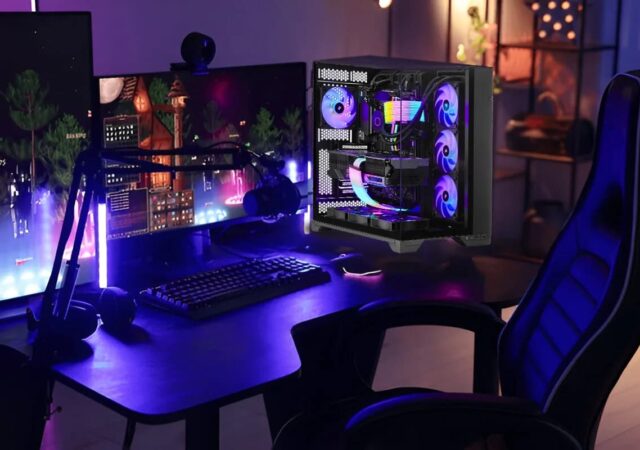 Bureau gaming avec PC transparent aux composants RGB, double ecran, clavier mecanique et fauteuil gamer dans une ambiance bleu violet
