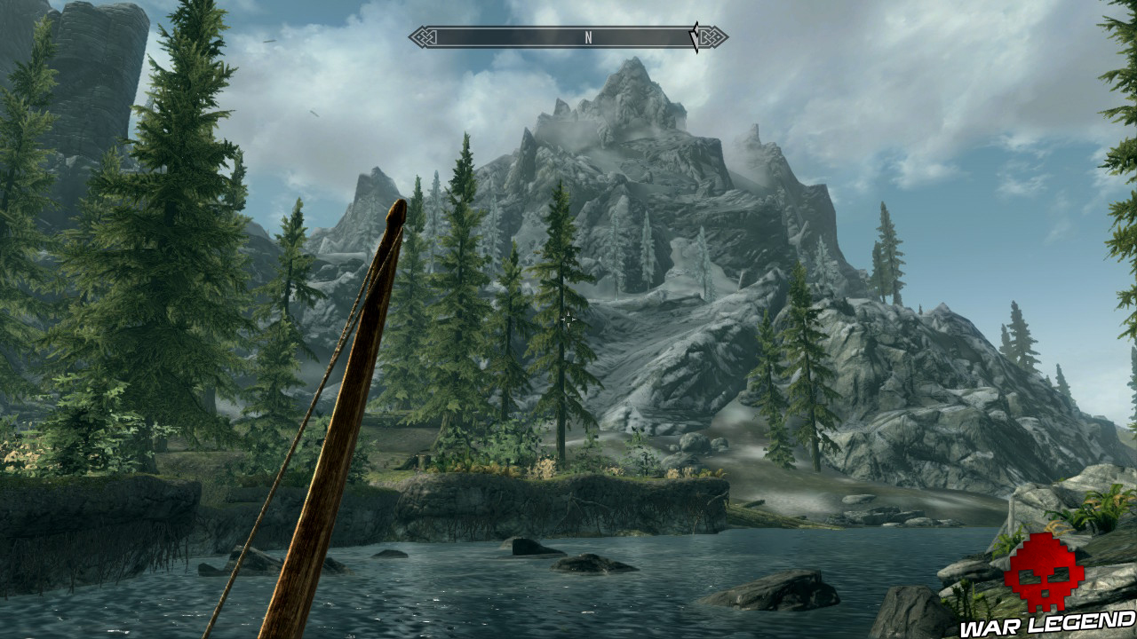 montagne dans les brumes et les nuages, arbres et rivière au premier plan